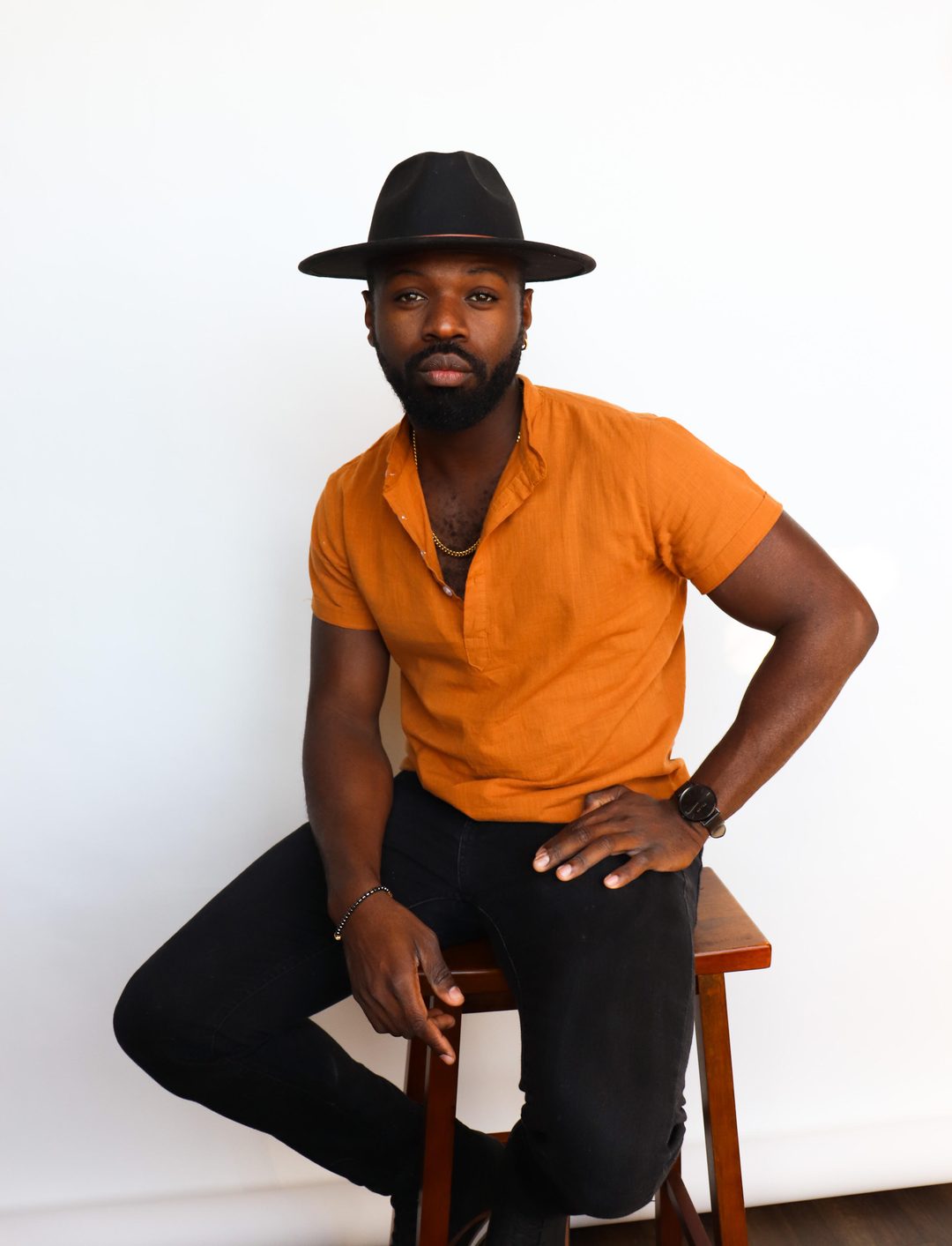 dj Darko in a wide-brim hat and orange shirt, seated